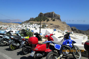 Ansicht der Akropolis von Lindos vom Parkplatz fotografiert wo man hier auf dem Bild Motorräder sieht die man sich auf der Insel Rhodos für Ausflüge mieten kann.