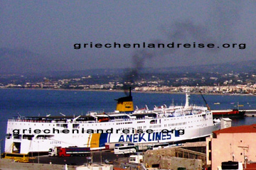 Autofähre der Anek Lines in einem Hafen auf einer griechischen Insel. Schön zu sehen wie gerade ein Bus und mehrere Lastwagen auf die Fähre fahren, aus deren Schornstein schon schwarze Rauchwolken abgehen.