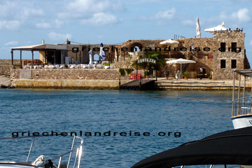 Chania, Restaurant Fortezza am Old Venetian Harbour. Hier kann man gemütlich und auch windgeschützt unter Sonnenschirmen sitzen und den Blick auf das offene kretische Meer oder über den Hafen auf die Altstadt schweifen lassen.