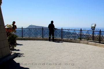 Aussichtspunkt vom Filerimos Berg an dem übergroßen Kreuz mit der kleinen Kapelle. Am Geländer der Plattform zu erkennen, ein Feuerwehrmann der nach Waldbränden Ausschau hält und ein Mann der seine Frau fotografiert.