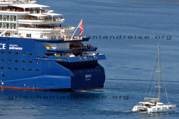 Das blaue Heck von einem Kreuzfartschiff das geradewegs in den Hafen von Korfu Stadt hinein fährt und dahinter ein Katameran der die Route kreuzt, so kann man auch korfu Anreisen, mit dem Schiff.