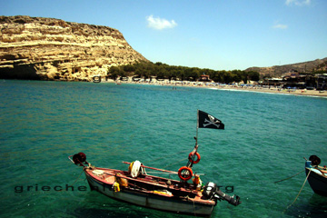 Das sieht man oft auf der griechischen Insel Kreta. Sichelförmige Strände so wie diese Bucht. Im Vordergrund ein kleines Boot mit einer schwarzen Seeräuberflagge. Der Totenkopf und die gekreuzten Knochen. Davon habe ich noch mehr Bilder gemacht. Auf Kreta gibt es nämlich auch nach gebaute Piratenschiffe, die man buchen kann.
