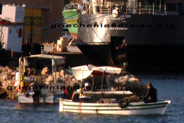 Ein Taucher in seinem Neopren-Taucheranzug wird von einem Fischer mit einem kleinen Boot zu den Tauchgründen vor der Insel Kreta gefahren.