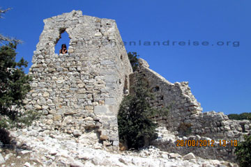 Eine Touristin schaut aus dem Fenster vom Haus in dem einst im Mittelalter die Mönche der Monolithos Ritterburg auf der Insel Rhodos schliefen.