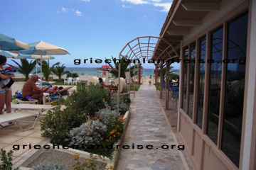 Der Garten neben dem Swimmingpool mit Nachbildungen von alten Griechischen Säulen, der Strandbar und dem Zugang zum Strand hinter dem Odyssia Beach Hotel in Rethymnon auf der Insel Kreta in Griechenland.