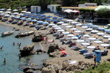 Der blaue Kasten im Vordergrund rechts im Bild mit dem Dach das ist eine Umkleidekabine an einem Strand auf der Insel Rhodos und im Hintergrund die Toiletten.