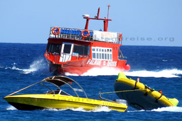 Wassersportart auf der Insel Rhodos. Touristen lassen sich in einem gelben runden Schlauchboot hinter einem Motorboot mit hoher Geschwindigkeit auf dem Meer hinterher ziehen, das kühlt ab und macht sehr viel Spass.