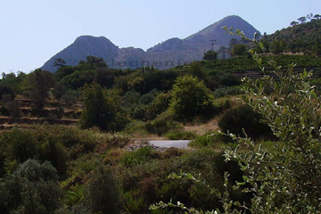 Ansicht vom Gipfel des Berges Lazaros auf der Insel Samos wo in der Nähe das Kloster Vronta liegt. Man erkennt ein kleines Bauernhaus zwischen einer Obstplantage als Terrassenfeld angelegt und im Hintergrund die unbewaldeten Flanken vom Berggipfel.