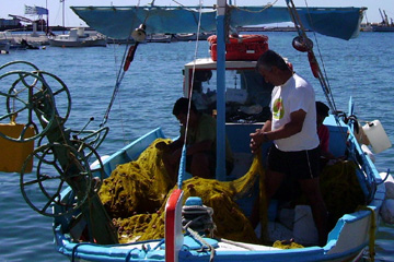 Fischer beim reparieren ihres Fischernetzes auf dem kleinen Fischerboot auf der Insel Samos in der Ägäis in Griechenland.