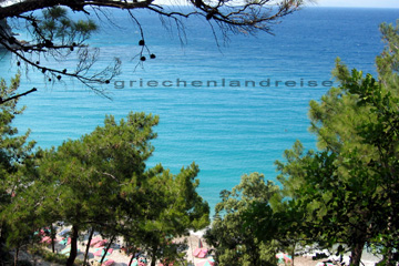 Blick bei der Radtour durch die Bäume auf den Strand an einer Bucht auf der Insel Samos beim Griechenland Urlaub.